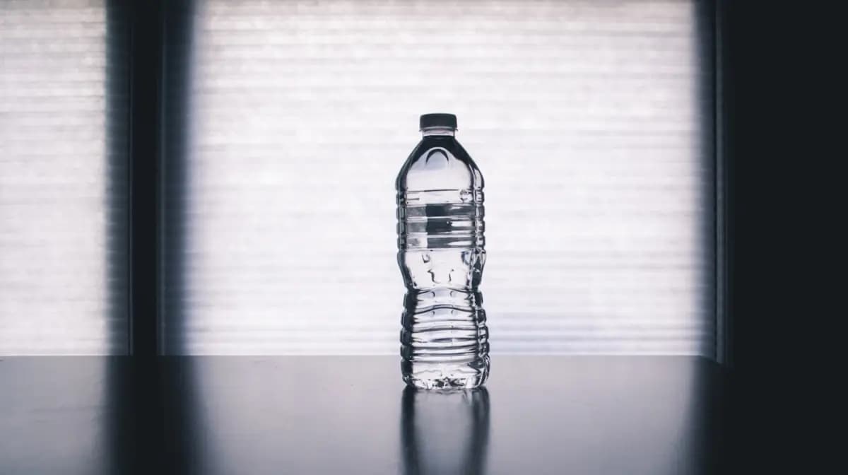 Botella de agua a contraluz sobre una superficie oscura